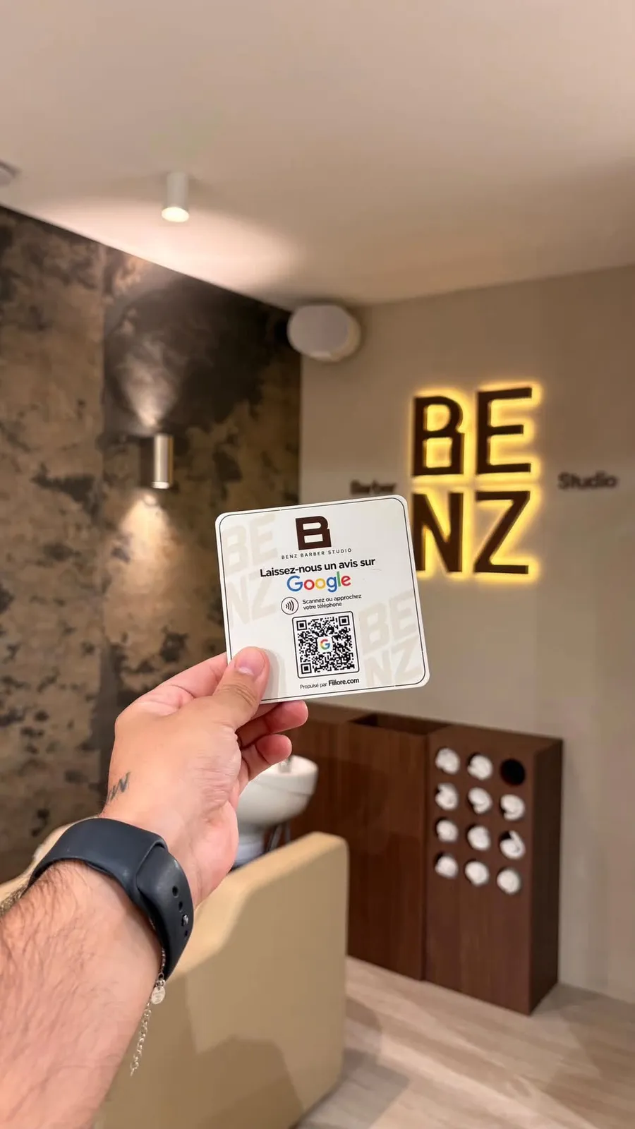 Plaque Avis Google de Benz Barber Studio tenue devant l'enseigne lumineuse du salon
